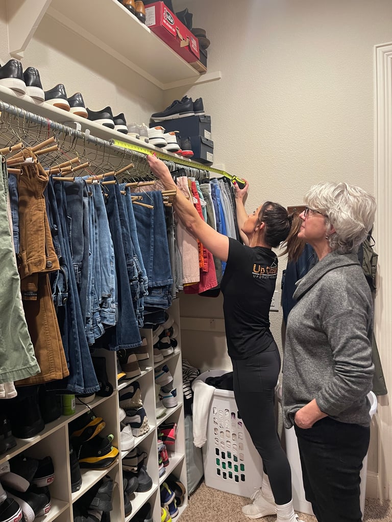 Two women organizing a closet with clothes on hangers, shelves, and storage bins